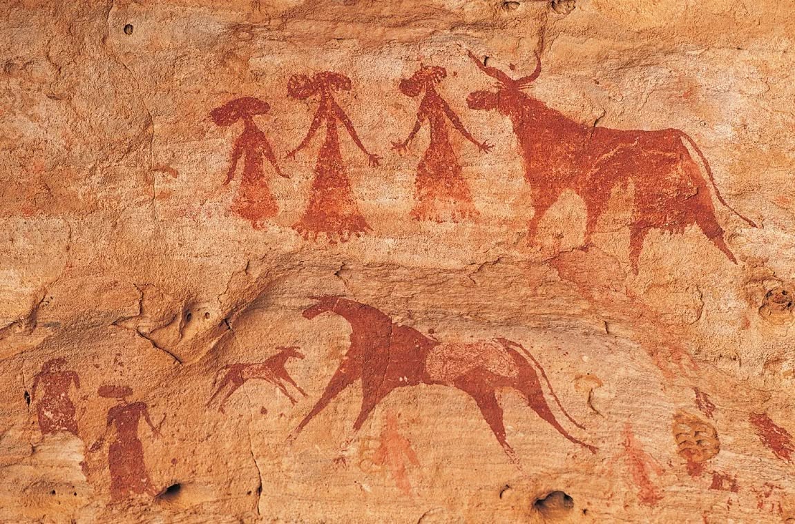 Stone Age cave paintings showing red ochre figures of humans and animals on cave wall